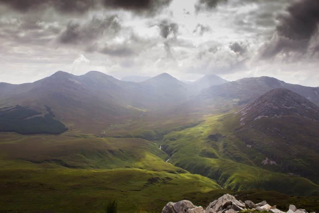 Green mountain valley in Ireland under dramatic storm clouds